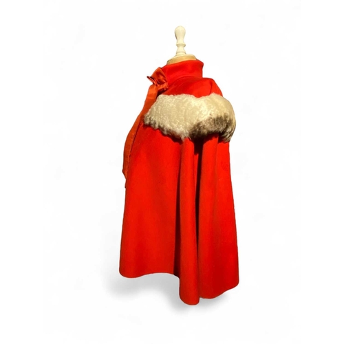 595 - ± K Fillingham Milliners Wool cape & mannequin In left hand shop window display, a red wool felt cap... 