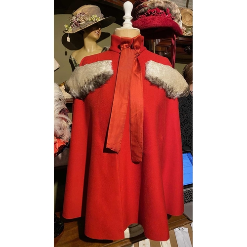 595 - ± K Fillingham Milliners Wool cape & mannequin In left hand shop window display, a red wool felt cap... 