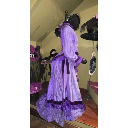 605 - ± K Fillingham Milliners A mannequin wearing a purple silk Victorian day dress A black fabric covere... 