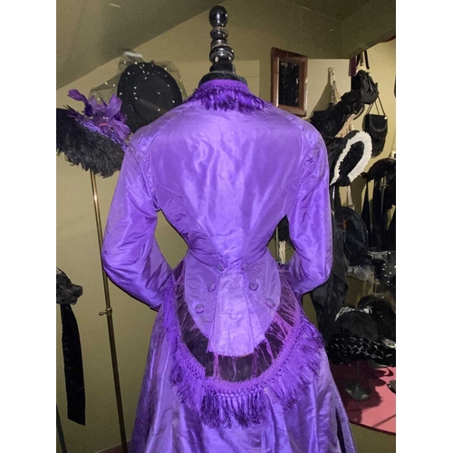 605 - ± K Fillingham Milliners A mannequin wearing a purple silk Victorian day dress A black fabric covere... 