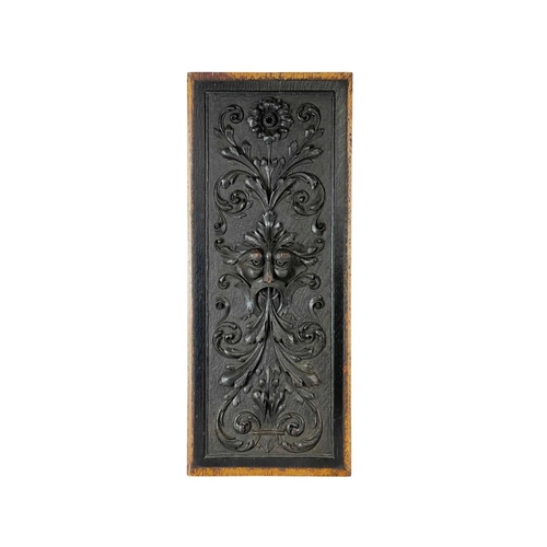 16 - A carved oak green man panel. 19th century, with a central mask below a single flowerhead and scroll... 