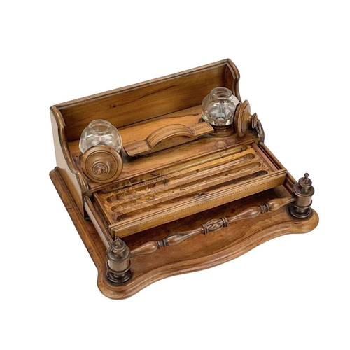 30 - A late Victorian olive wood desk stand. The two glass inkwells with turned covers, above two narrow ... 