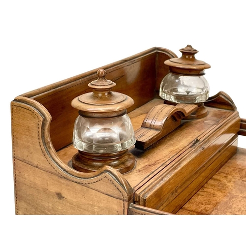 30 - A late Victorian olive wood desk stand. The two glass inkwells with turned covers, above two narrow ... 