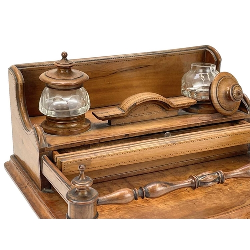 30 - A late Victorian olive wood desk stand. The two glass inkwells with turned covers, above two narrow ... 