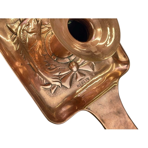 44 - A Newlyn copper chamber candlestick. With a square base, repousse decorated with two fish, with a sh... 