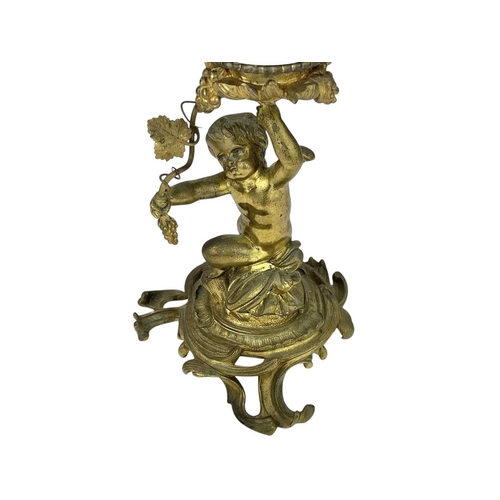 61 - A 19th century gilt brass cherub oil lamp. The opaque glass reservoir on a grape and vine base with ... 