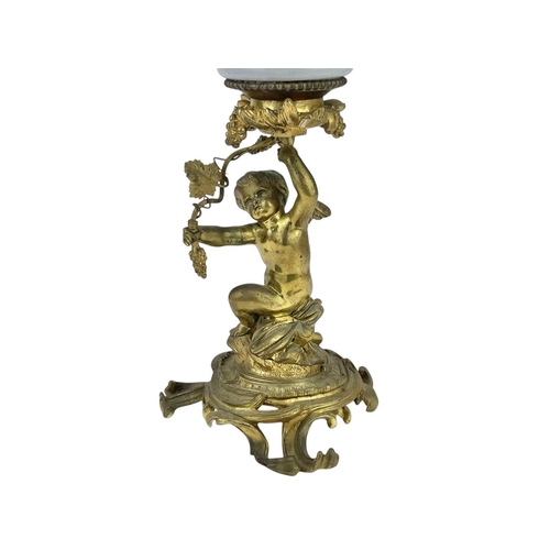 61 - A 19th century gilt brass cherub oil lamp. The opaque glass reservoir on a grape and vine base with ... 