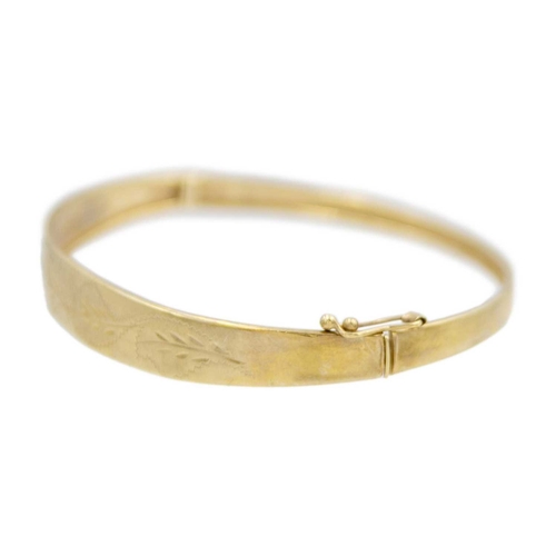 145 - A 9k oval hinged bangle with leaf-cut decoration. Stamped 375, width 64mm, 6.5g.