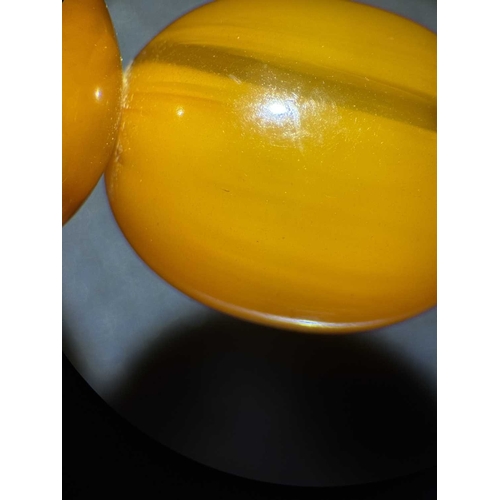 171 - A graduated butterscotch 'amber' style necklace. The oval beads are 8mm-23mm, forty-nine beads, scre... 