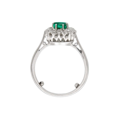 30 - An emerald and diamond set white gold cluster ring. A rectangular step-cut, vivid, saturated green e... 