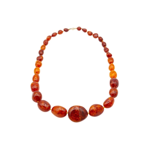 46 - A large graduated heat-treated cognac amber bead necklace with a pair of earrings. 'Sun spangles' in... 