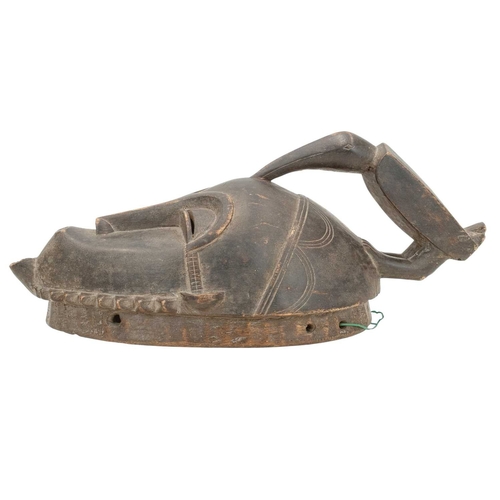 10 - An African Baule ancestor mask. Surmounted by a toucan, with arched eyebrows over slit pierced eyes,... 