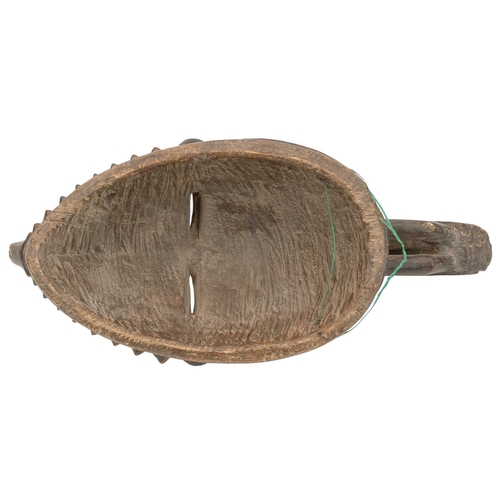10 - An African Baule ancestor mask. Surmounted by a toucan, with arched eyebrows over slit pierced eyes,... 