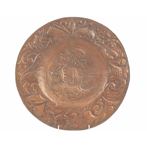 201 - An Arts and Crafts copper charger, John Pearson style. The central well repousse decorated with a ga... 