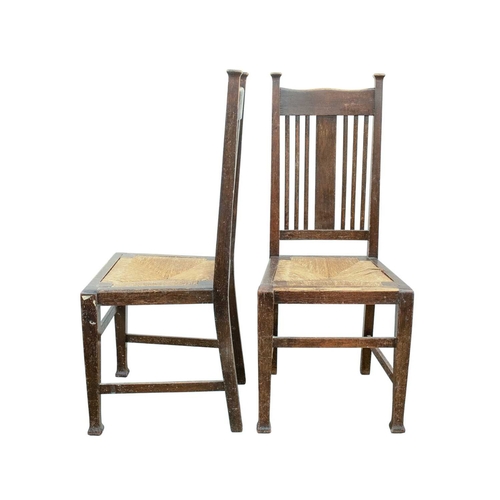 205 - A pair of Arts and Crafts oak dining chairs. To a design by Charles Voysey, with shaped top rails, v... 