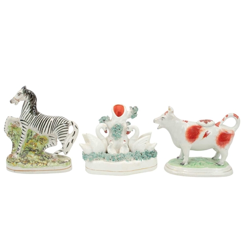 278 - Four Staffordshire pottery animal figures. Includes a Zebra, height 16cm, a swan family spill vase, ... 