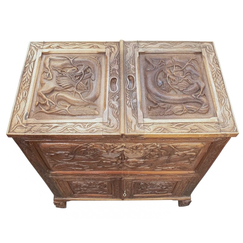 369 - A Chinese carved teak drinks or cocktail cabinet. Mid 20th century, with twin hinged compartments op... 