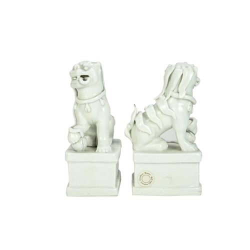 372 - A pair of Chinese blanc de chine Buddhistic lions. Qianlong, each beast rests its paw upon a ball, o... 