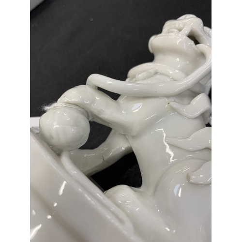 372 - A pair of Chinese blanc de chine Buddhistic lions. Qianlong, each beast rests its paw upon a ball, o... 