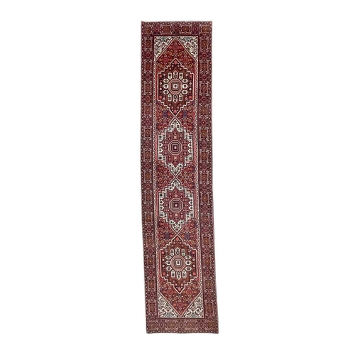 466 - A Persian runner. Late 20th century, wool pile on cotton, red ground with four central medallions, 3... 