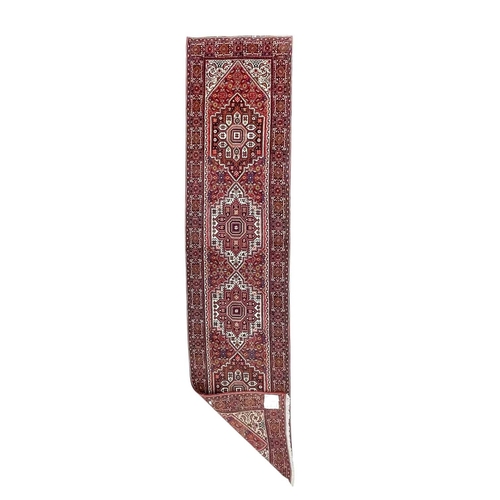 466 - A Persian runner. Late 20th century, wool pile on cotton, red ground with four central medallions, 3... 