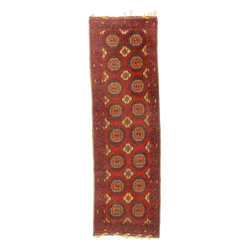 481 - An Afghan wool carpet runner. Red ground, repeating central guls within multiple patterned borders, ... 