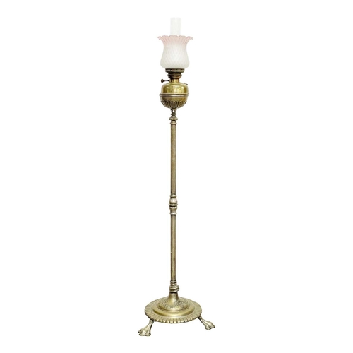 524 - A Victorian brass standard oil lamp. Raised on a circular cast base with three lion's paw feet, with... 