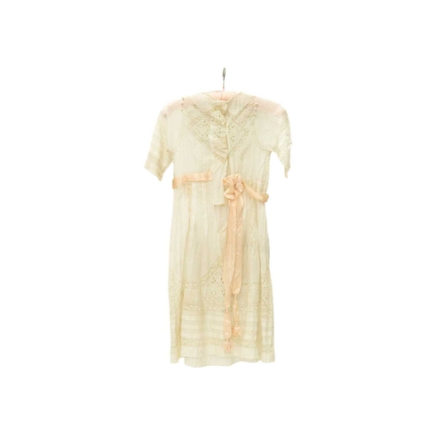 566 - A girl's dress, circa 1900. White muslin with whitework embroidery and lace panels, mother of pearl ... 