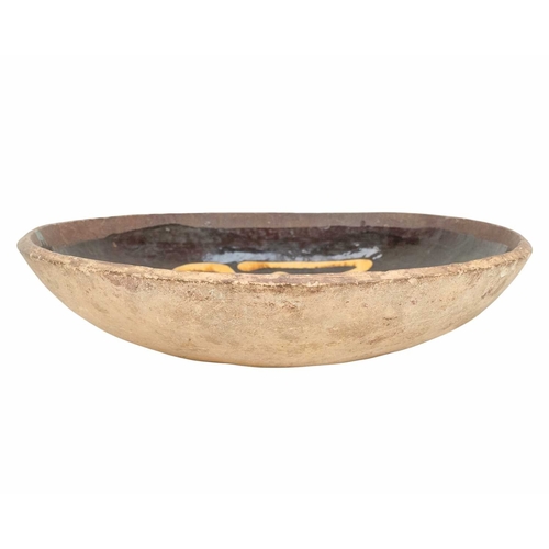 622 - An English slipware pottery colander or strainer dish. Late 18th century, the chocolate ground with ... 