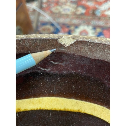 622 - An English slipware pottery colander or strainer dish. Late 18th century, the chocolate ground with ... 