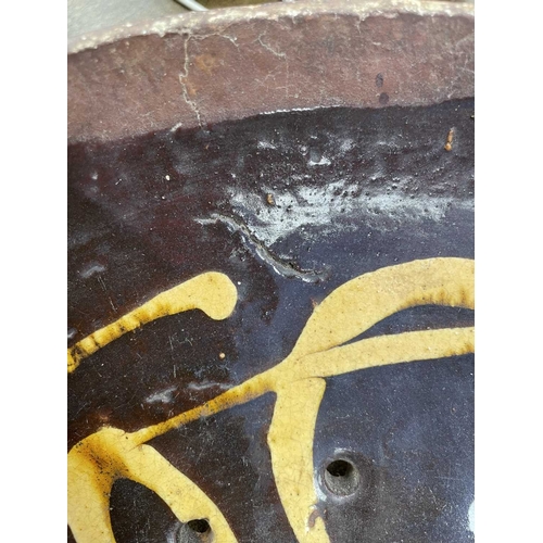 622 - An English slipware pottery colander or strainer dish. Late 18th century, the chocolate ground with ... 