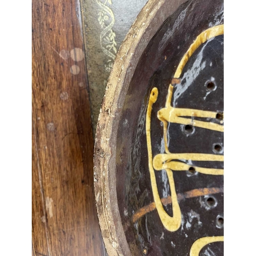 622 - An English slipware pottery colander or strainer dish. Late 18th century, the chocolate ground with ... 