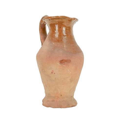 640 - An English post-medieval redware earthenware jug. The clear glazed interior extends to the handle an... 