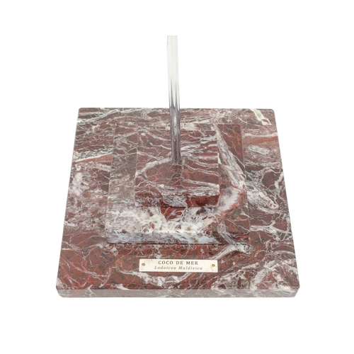 66 - A polished coco de mer. Bisected and mounted for display on a steel rod and a stepped marble base, h... 