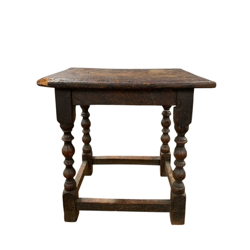 695 - A 17th century oak joint stool. The figured top with a moulded edge and raised on reel and bobbin tu... 