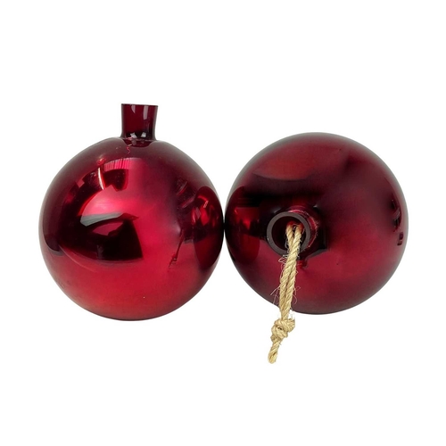 714 - A pair of red glass witch balls. 20th century, mirrored glass with pronounced rims, each approx 20cm... 