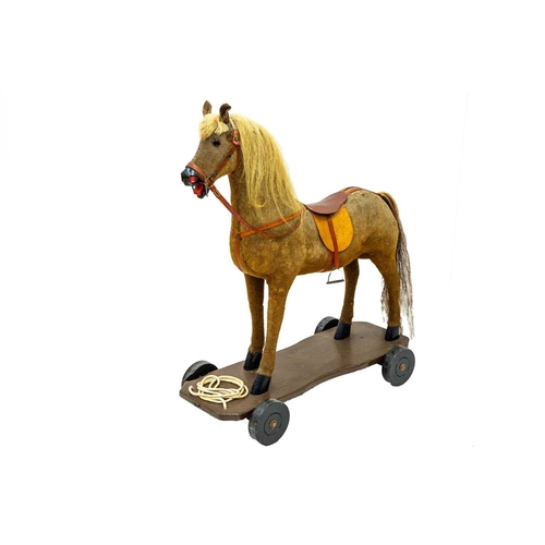 720 - A child's pull-along toy horse. 20th century, fabric covered wood with later saddle, bridle and fitt... 