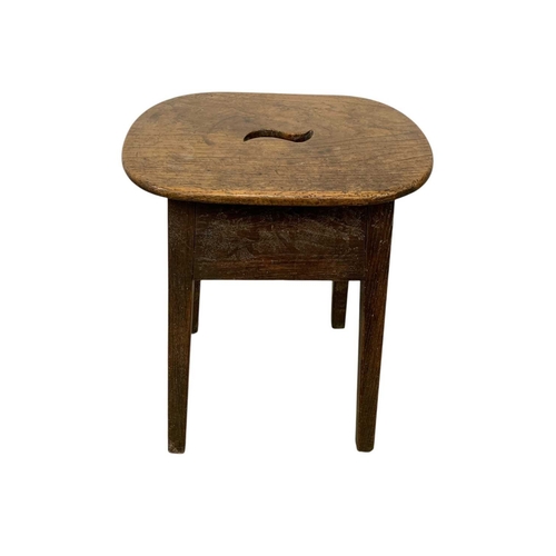 723 - A George III elm and oak stool. The top pierced with a central aperture, raised on square moulded le... 