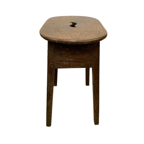 723 - A George III elm and oak stool. The top pierced with a central aperture, raised on square moulded le... 