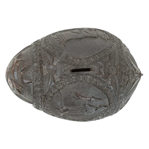 750 - A carved coconut bugbear money box. 19th century, with four carved panels of figures, male and femal... 