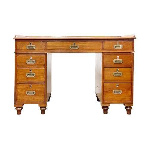 908 - A Victorian campaign type teak pedestal desk. With a raised three-quarter gallery, fitted with nine ... 