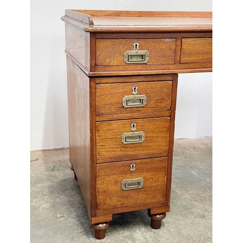 908 - A Victorian campaign type teak pedestal desk. With a raised three-quarter gallery, fitted with nine ... 
