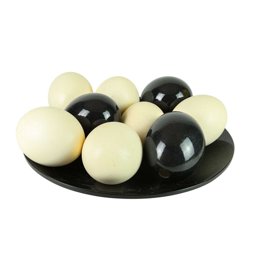 92 - A group of nine ostrich eggs. Natural and three with a lacquered finish, displayed on a lacquered di... 