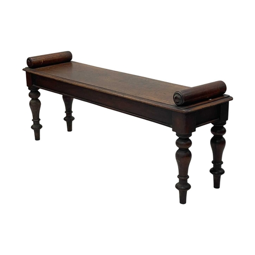 926 - A Victorian mahogany hall bench. The plank top with a moulded edge and cylinder turned ends, raised ... 