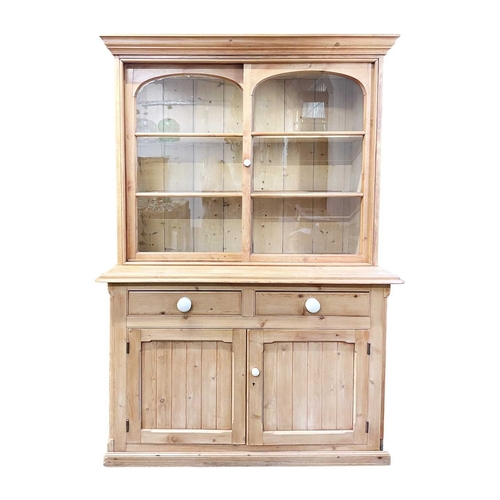 946 - A late Victorian pine dresser. With plate rack with panelled back, fitted with two glazed sliding do... 