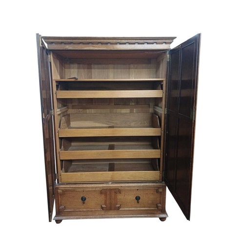 968 - An oak press cupboard. Early 20th century, the panel doors enclosing five sliding shelves, with a dr... 