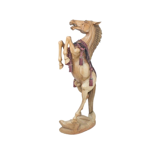 102 - A large carved hardwood figure of a rearing stallion. Late 20th century, standing on a naturalistic ... 