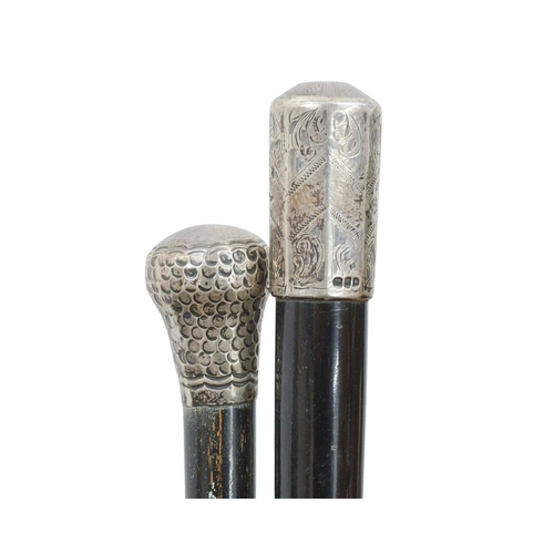23 - A collection of walking sticks and canes in an Art Nouveau oak stand. Including two silver topped eb... 