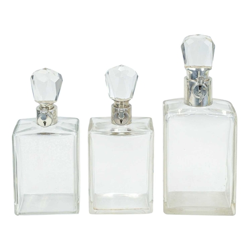 295 - A matched suite of three Hukin & Heath silver mounted locking decanters. George V, each of plain rec... 