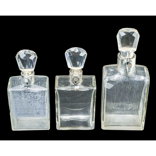 295 - A matched suite of three Hukin & Heath silver mounted locking decanters. George V, each of plain rec... 